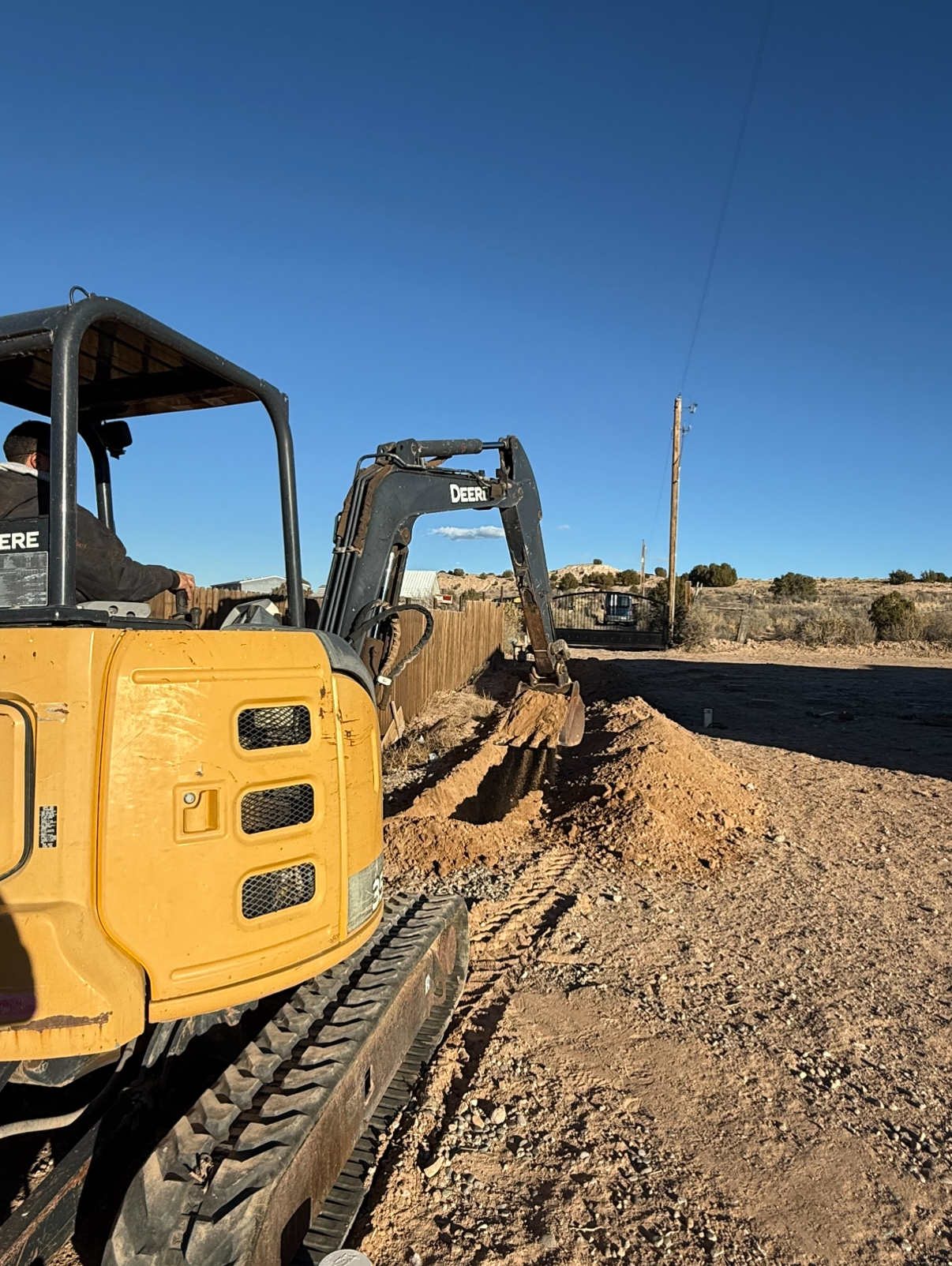 Yellow mini-excavator digging a trench