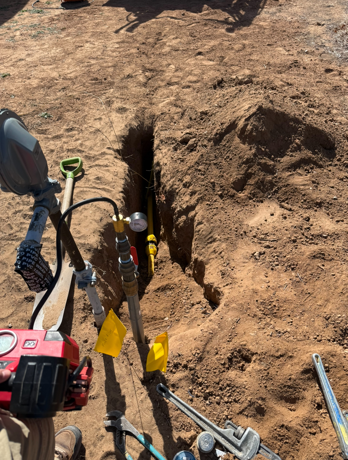 Trench with a yellow gas line and pressure gauge