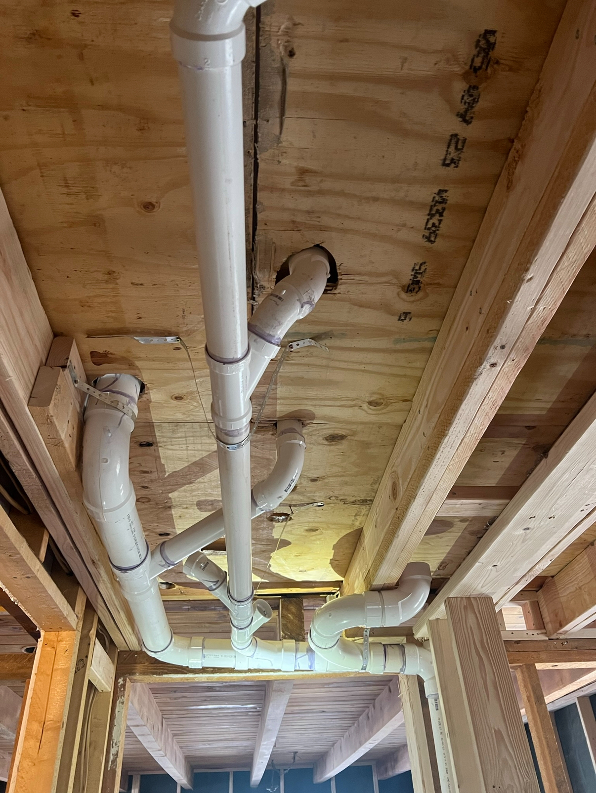 PVC plumbing pipes run under a subfloor