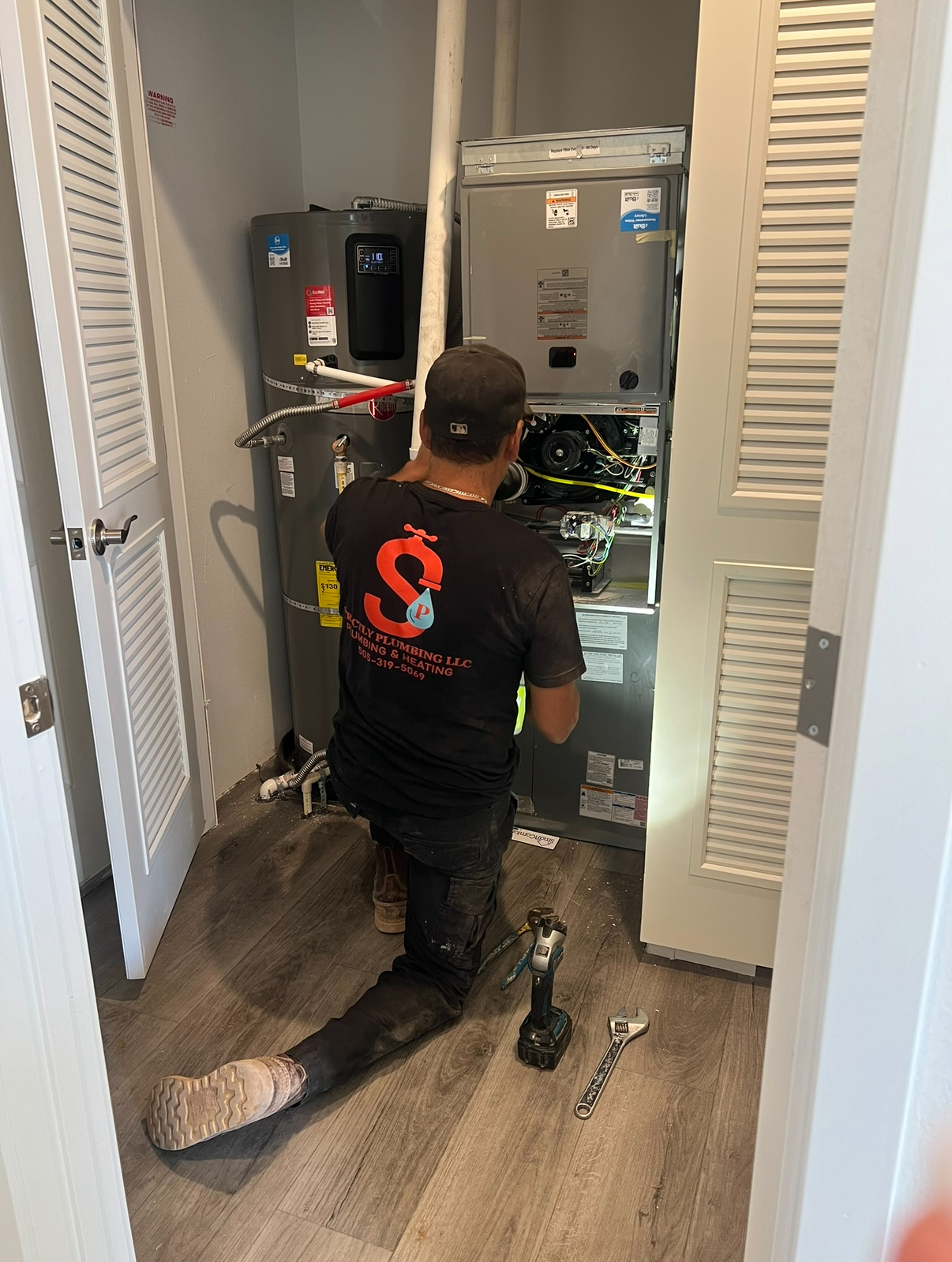 A licensed Strictly Plumbing technician servicing a furnace and water heater